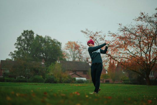 Young man swinging golf club with winter golf apparel on